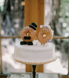 two donuts sitting on top of a white frosted cake