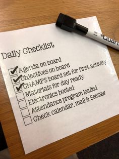 a daily checklist is placed on top of a wooden table next to a pen