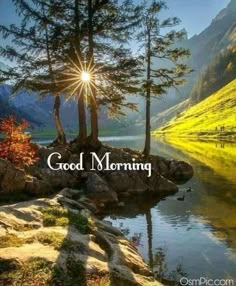 the words good morning are in front of a lake with trees and mountains behind it