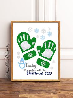 a baby's first christmas hand and foot print is displayed in front of a wooden frame