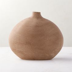 a brown vase sitting on top of a white table