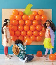 two girls are playing with oranges on the wall in front of an advertisement for children's clothing