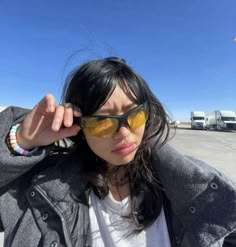 a woman wearing sunglasses is posing for the camera with her hand on her head and looking off into the distance