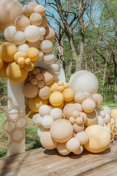 a bunch of balloons that are sitting on a wooden table in front of some trees