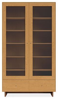 a wooden bookcase with glass doors on the front and bottom shelves, against a white background