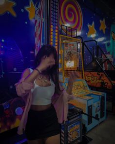 a woman standing in front of an arcade machine with her hands up to her face