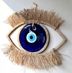 an eyeball hanging on a wall with straw and blue glass in the iris's eye