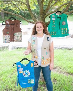 a woman standing in front of a tree holding two bibs