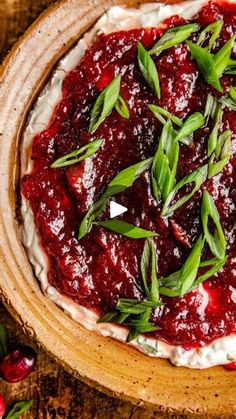 a wooden bowl filled with whipped cream and cranberry sauce on top of a table