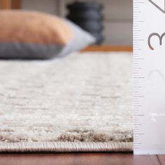 a white rug with a ruler on it next to a pillow and bed in the background