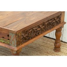 an old wooden table with carvings on the top and bottom, sitting in front of a door