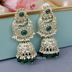 A pair of golden-toned Soundarya Kundan Jhumka Earrings – Green Earrings for Girls with hanging pearls. Size & Other Details Length :  10cm Weight : 32gm/pc Material  : Alloy, Pearl, Kundan, Stone work Shape : Drop Shape Attire :  Lehenga Choli, Salwar Suit, Kurti, Saree, Flared Dress Festive Green Jhumkas For Pierced Ears, Festive Green Jhumkas, Green Pearl Earrings For Festivals, Green Pearl Drop Earrings For Festivals, Pearl Jhumkas, Kundan Jhumka Earrings, Kundan Jhumka, Suit Kurti, Celebrity Jewelry