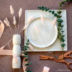 the table is set with white plates, flowers and ribbon for decoration or as centerpieces