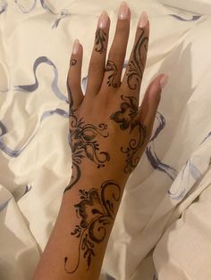 a woman's hand with tattoos on it laying on a white sheet covered bed