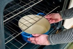 a person is holding a blue pot in an oven with the door open to show it's water inside