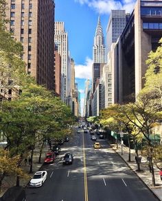 an empty city street with tall buildings and cars parked on the side of the road