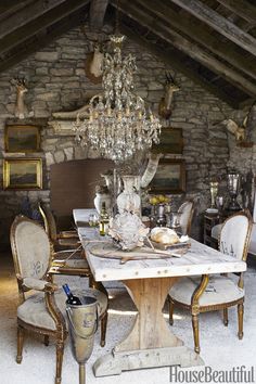 an old fashioned dining room with stone walls and exposed ceiling, chandelier hanging from the rafters