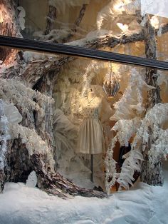 a window display with snow covered trees and mannequins