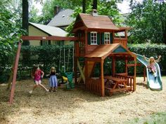 two children playing on a wooden swing set in the yard with a slide and climbing frame