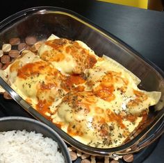 a casserole dish with meat and cheese in it next to rice on a table