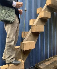 a man standing on top of a wooden stair case next to a blue container with a string hanging from it