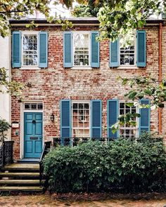 a brick house with blue shutters and steps leading up to the front door is shown