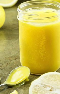 a glass jar filled with yellow liquid next to sliced lemons