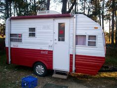 a red and white trailer parked in the woods