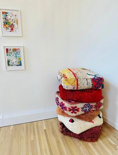 a stack of blankets sitting on top of a hard wood floor next to a white wall