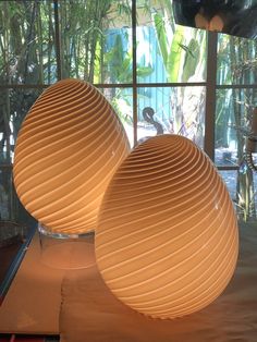 two large white vases sitting on top of a table next to a glass window