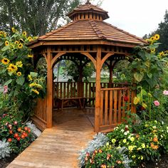 a wooden gazebo surrounded by flowers and trees