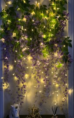 purple and green vines are hanging from the ceiling above a table with candles on it