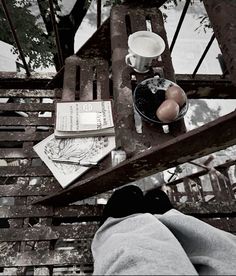 a person sitting on a bench with their feet propped up next to an open book