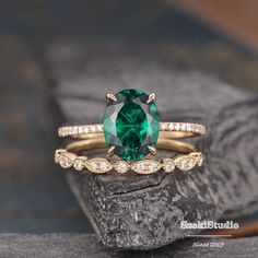 an emerald colored ring with diamond accents on the band and in front of a rock