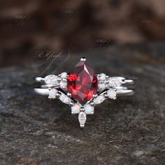 a close up of a ring with a red stone in the middle and white stones around it