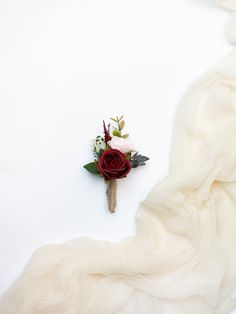 a boutonniere is laying on a white sheet