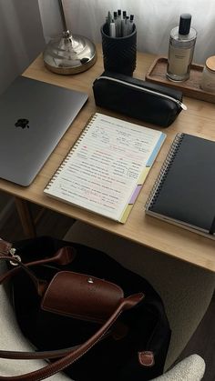 a desk with a laptop, notebook and other items on it