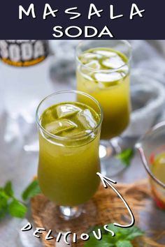 two glasses filled with green liquid sitting on top of a table