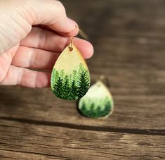 "These serene, stately pine trees in the mist are hand painted on lightweight wood earrings using acrylic paints. Perfect for nature lovers. Earring findings are 18k gold plated stainless steel.   Because these are hand painted, no two sets are exactly alike. The earrings you get may vary slightly from photos.  Dimensions: 2\" long 1 3/8\" wide Materials: Wood slice Acrylic paint Acrylic varnish Stainless steel 18K gold plated hook and jump ring Silicone rubber backs Shipping: Ready to ship for free within 1 business day!" Timber Earrings, Hand Painted Earrings Wood, Pine Tree Painting, Water Color Pencils, Pine Tree Forest, Pine Trees Forest, Acrylic Varnish, Hand Painted Earrings, Paint Acrylic