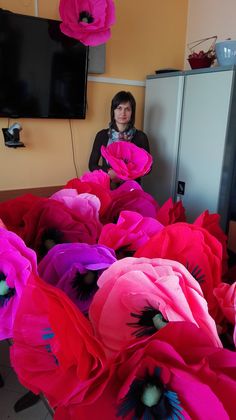 a woman sitting in front of a bunch of pink flowers on top of a table