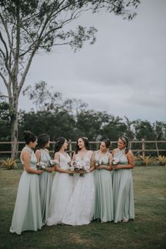 a group of women standing next to each other on top of a lush green field