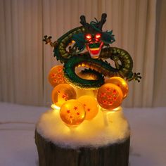 a dragon statue sitting on top of a wooden stump covered in snow and glowing lights