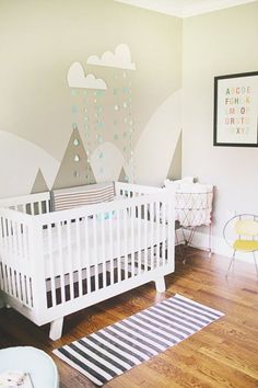 a baby's room with a white crib in the corner and mountains painted on the wall