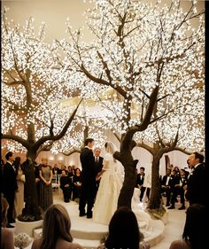 a bride and groom standing under a tree in front of an audience at a wedding