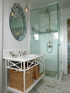 a bathroom with a sink, mirror and shower stall in the corner next to two wicker baskets