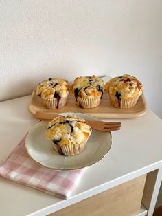 blueberry muffins sitting on top of a white plate next to a cutting board