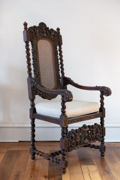 an old wooden chair sitting on top of a hard wood floor next to a white wall