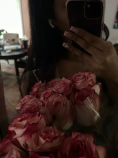 a woman taking a selfie with her cell phone surrounded by roses in front of her