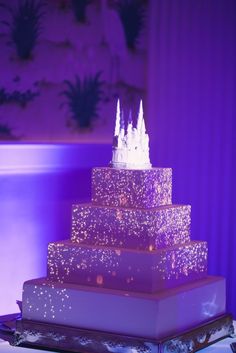 a wedding cake is lit up with purple lights