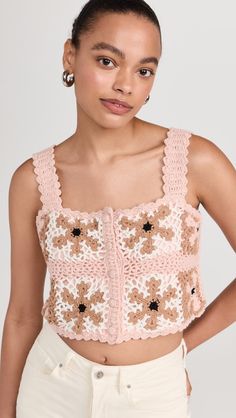 a woman wearing a crop top with crocheted flowers on the front and sides